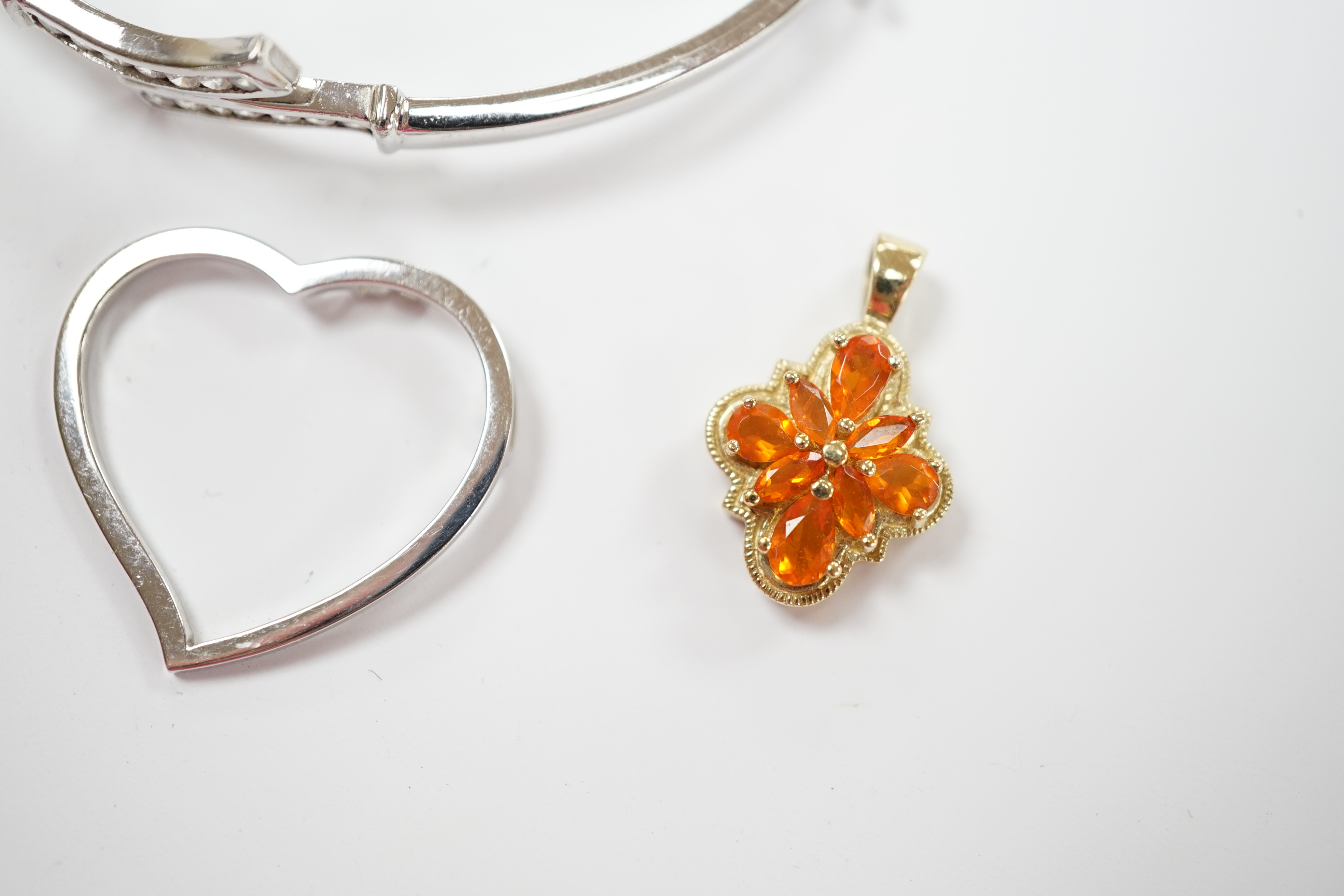 A 9ct white gold heart pendant, a 9kt bangle, two 9ct and gem set pendants and two yellow metal pendants.